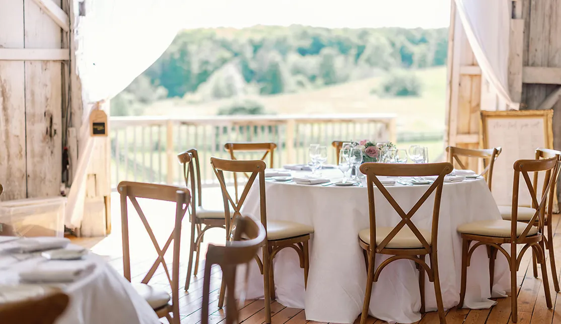 Elegant barn wedding reception table set with white linens and floral centerpiece