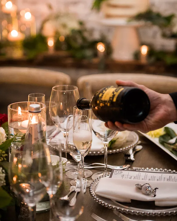Champagne poured at a formal dinner table with roses and candles