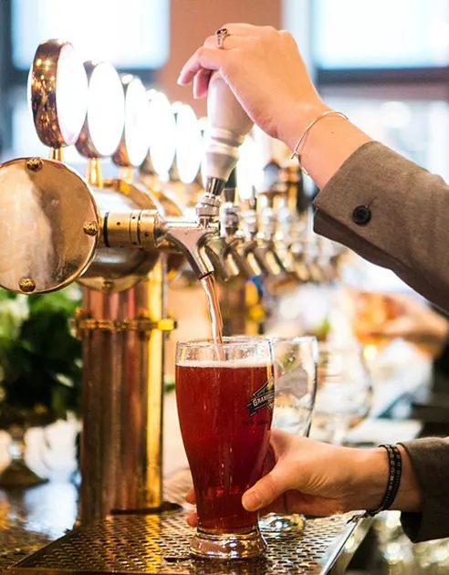 Bartender pouring craft beer from brass taps at an event bar