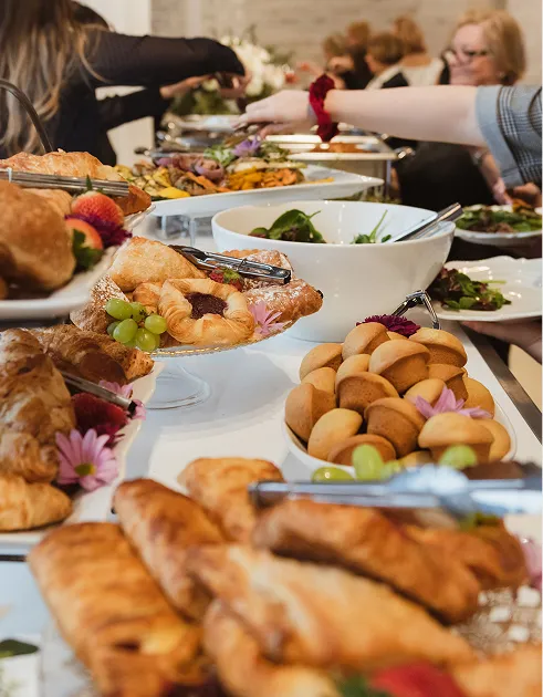 Brunch buffet with pastries, croissants, and fresh salad at a catered gathering