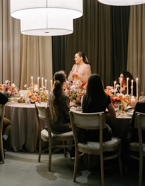 Guests at a candlelit dinner table with floral centerpieces