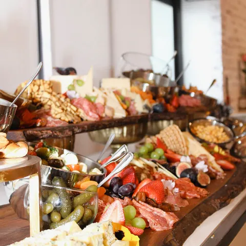 Two-tier charcuterie grazing table with cheeses, meats, and fresh fruit