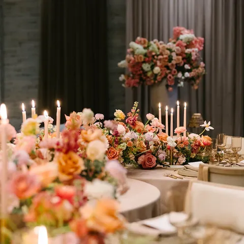 Candlelit banquet table with peach and coral floral centerpieces