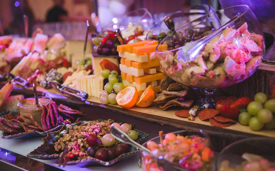 Multi-tier cheese and fruit grazing board under purple event lighting