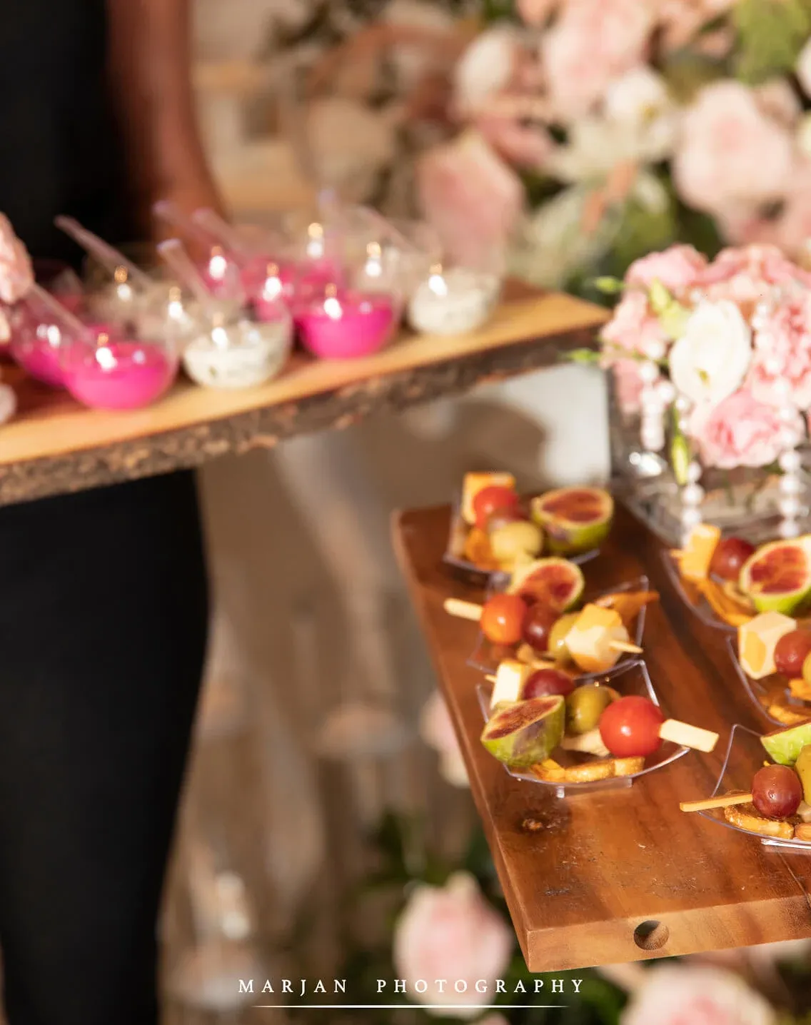 Passed fig-and-cheese skewers beside pink mousse cups on a wooden tray