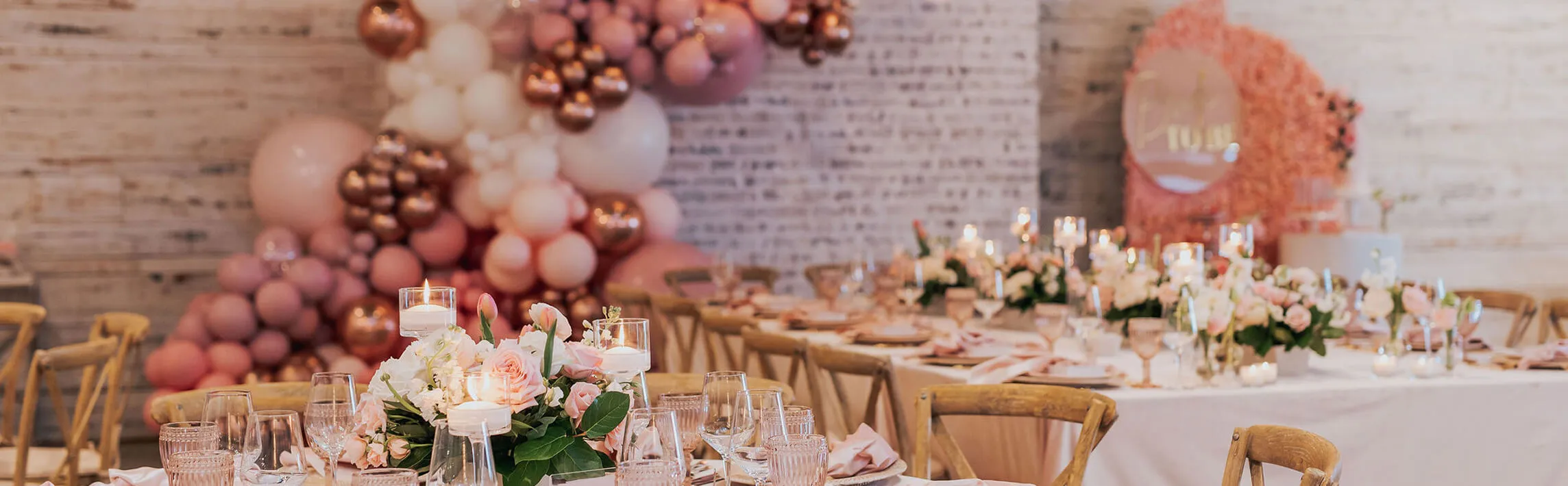 Bridal shower dining tables with pink florals, balloon wall, and Bride to Be backdrop