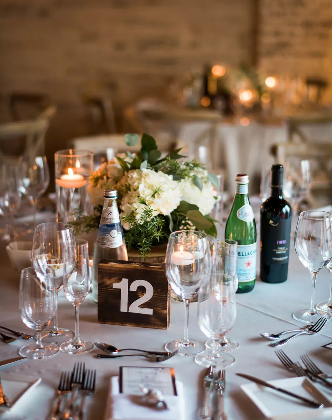Formal dinner table number 12 with white hydrangeas, floating candle, and menus