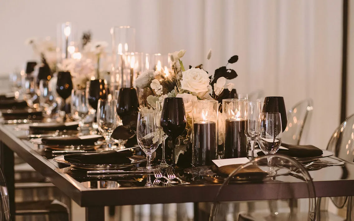Modern black-and-white table with silver chargers, black stemware, and pillar candles