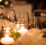 Champagne being poured into a flute at a candlelit dinner